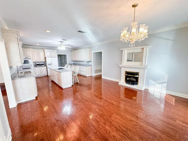 a living room with dining table wooden floor and a kitchen
