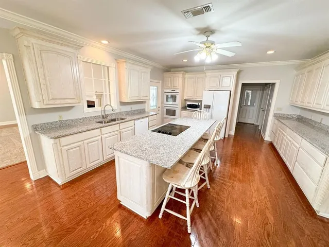 a kitchen with granite countertop kitchen island wooden floor center island and stainless steel appliances