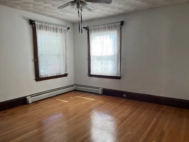 a view of an empty room with a window and wooden floor