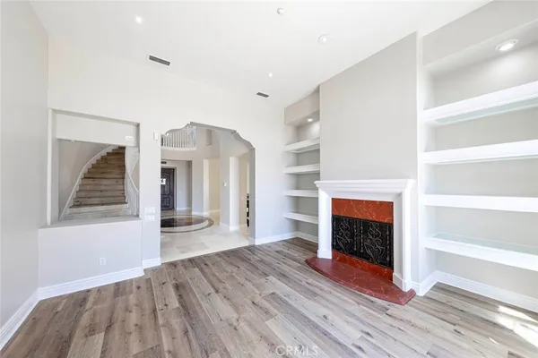 a view of an empty room with wooden floor fireplace and a window