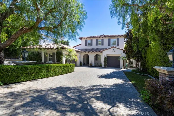 a front view of a house with a garden and trees