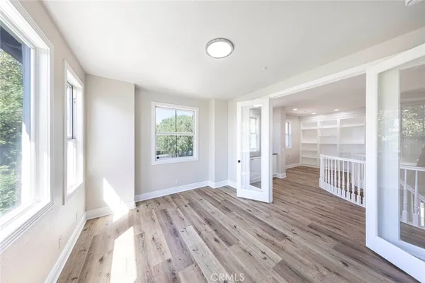 a view of empty room with wooden floor and fan