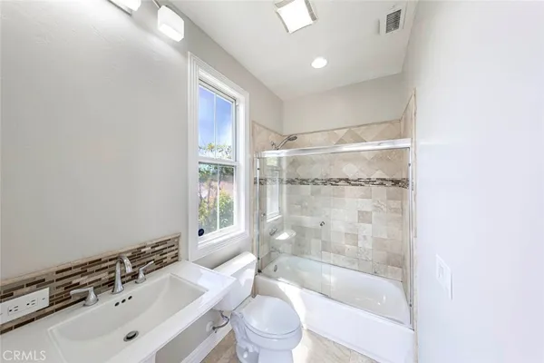 a bathroom with a bathtub shower sink mirror and toilet
