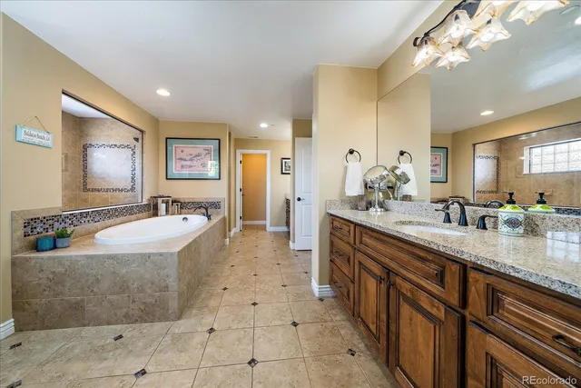 a spacious bathroom with a granite countertop sink a mirror and a bathtub