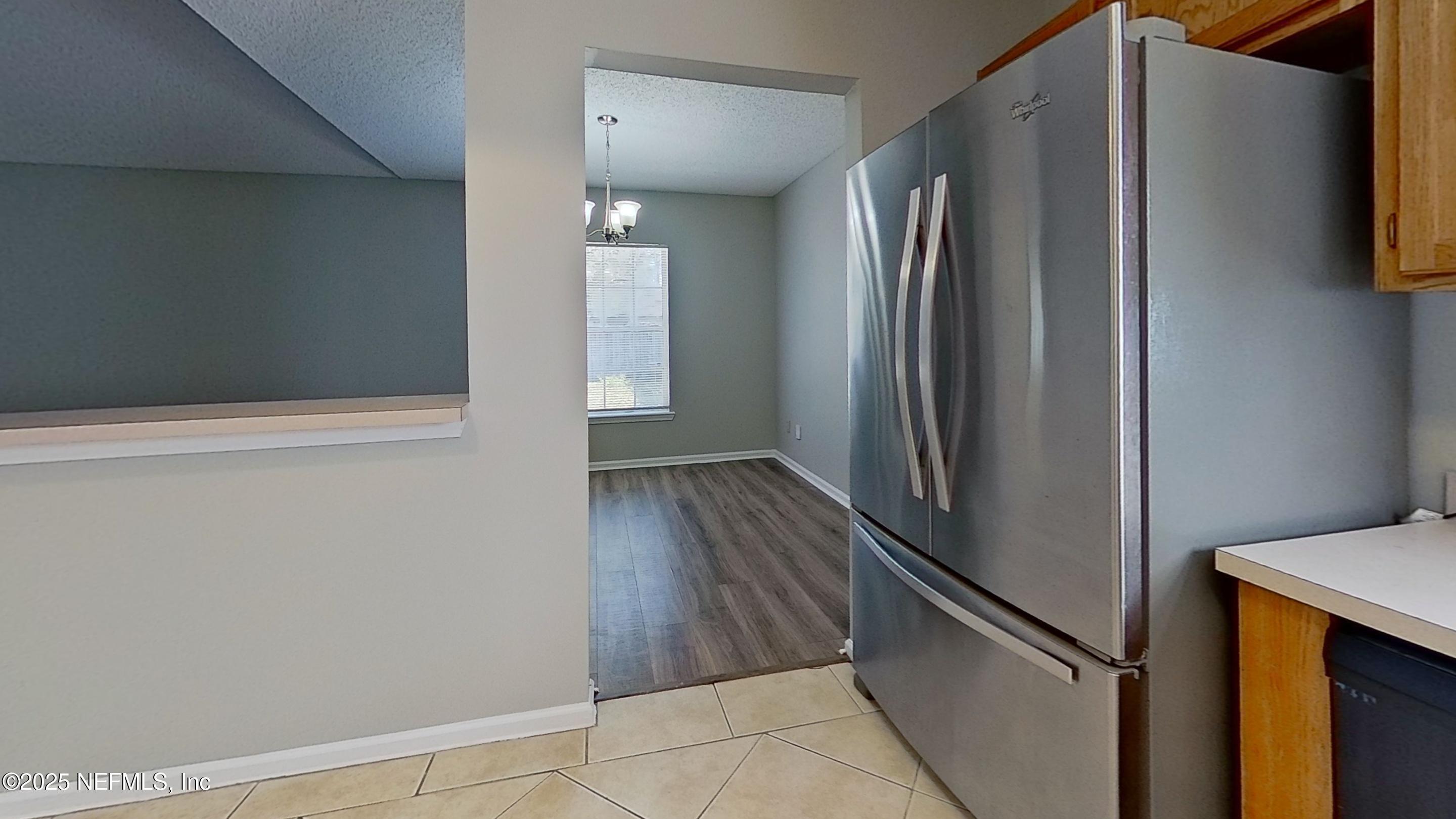 1639 Spring Branch Drive West Jacksonville, FL 32221 - Photo 7 of 25 a view of a refrigerator in kitchen and an empty room with wooden floor