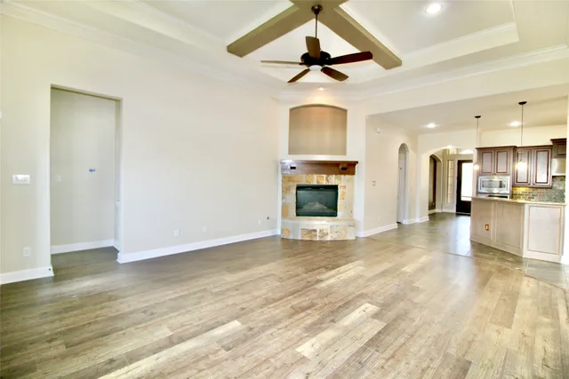 an empty room with wooden floor chandelier fan and windows