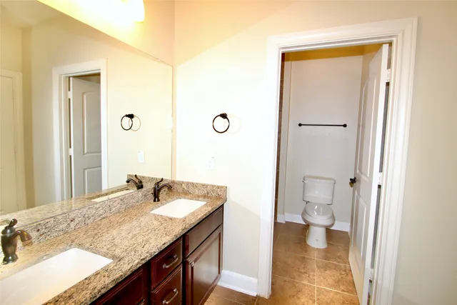 a bathroom with a granite countertop toilet sink and mirror
