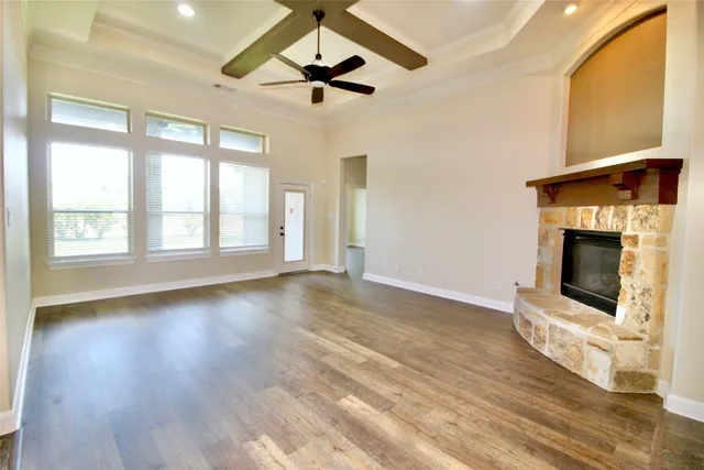 a view of an empty room with wooden floor fireplace and a window