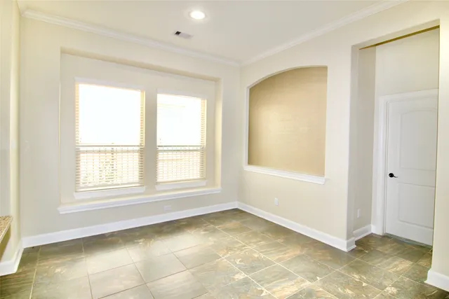 a view of an empty room and kitchen view with wooden floor