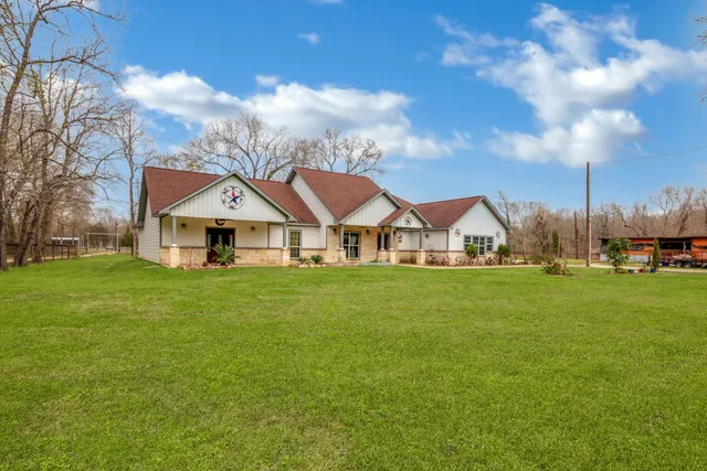 a view of a big house with a big yard and large trees