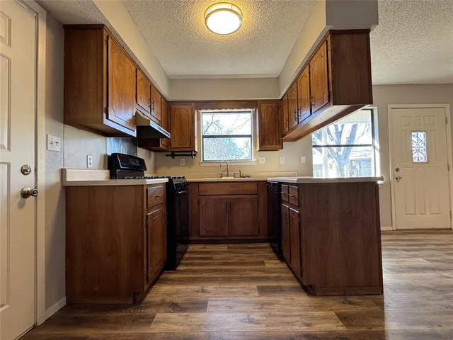 a kitchen with stainless steel appliances granite countertop a stove a sink dishwasher and a refrigerator with wooden cabinets