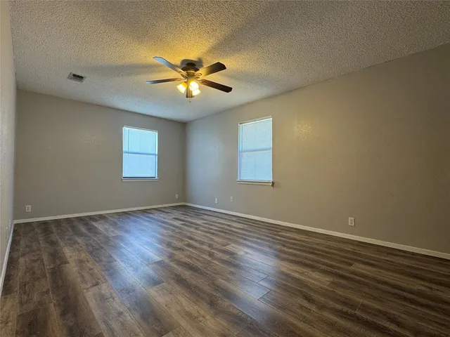 a view of an empty room with chandelier fan and wooden floor