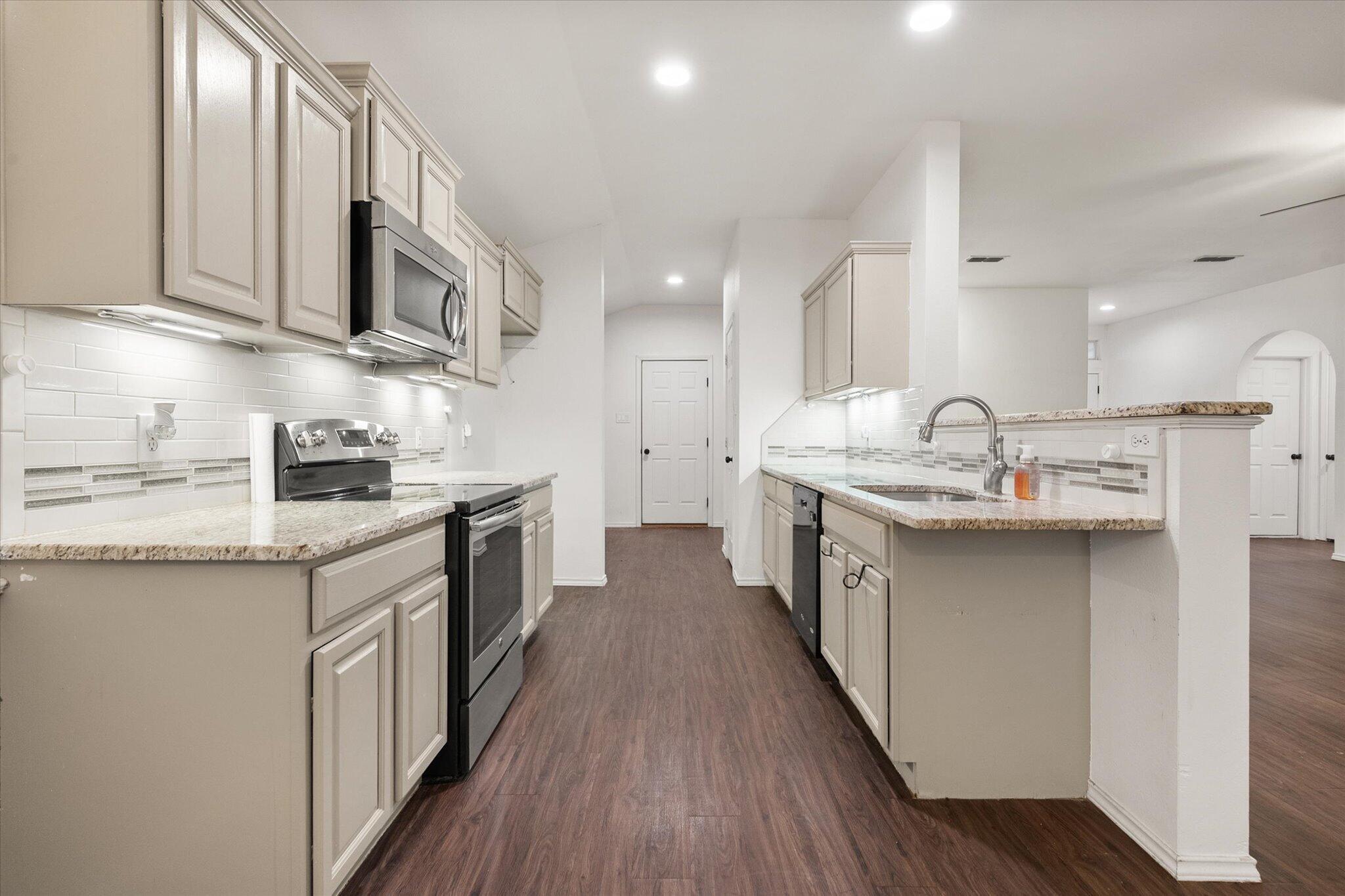6104 Duke Street Lubbock, TX 79416 - Photo 12 of 28 a kitchen with stainless steel appliances granite countertop a sink a stove top oven a counter space and cabinets