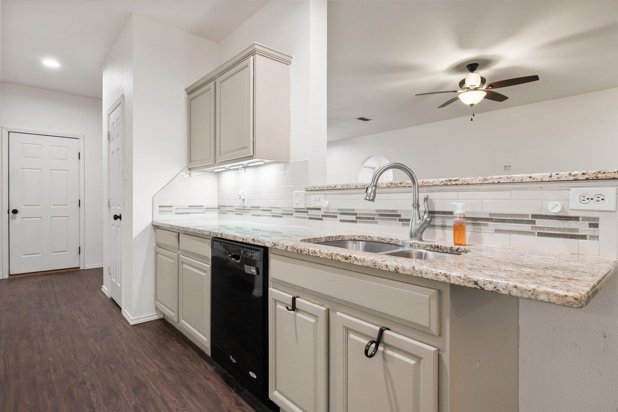 6104 Duke Street Lubbock, TX 79416 - Photo 13 of 28 a kitchen with stainless steel appliances granite countertop a sink dishwasher and white cabinets with wooden floor