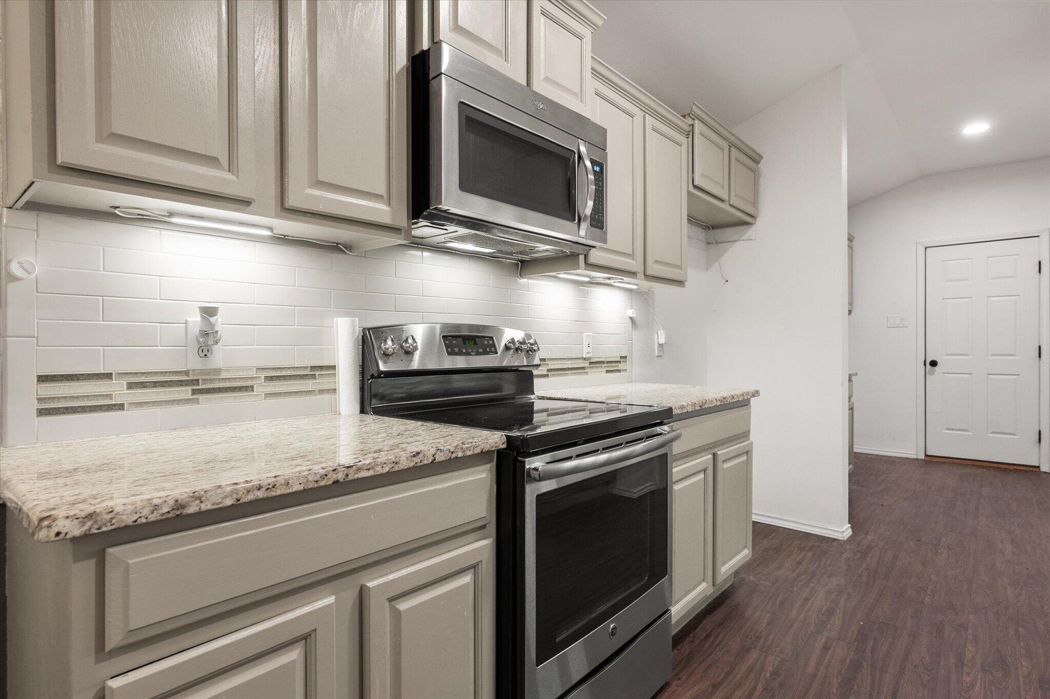 6104 Duke Street Lubbock, TX 79416 - Photo 14 of 28 a kitchen with stainless steel appliances granite countertop a stove a microwave and cabinets