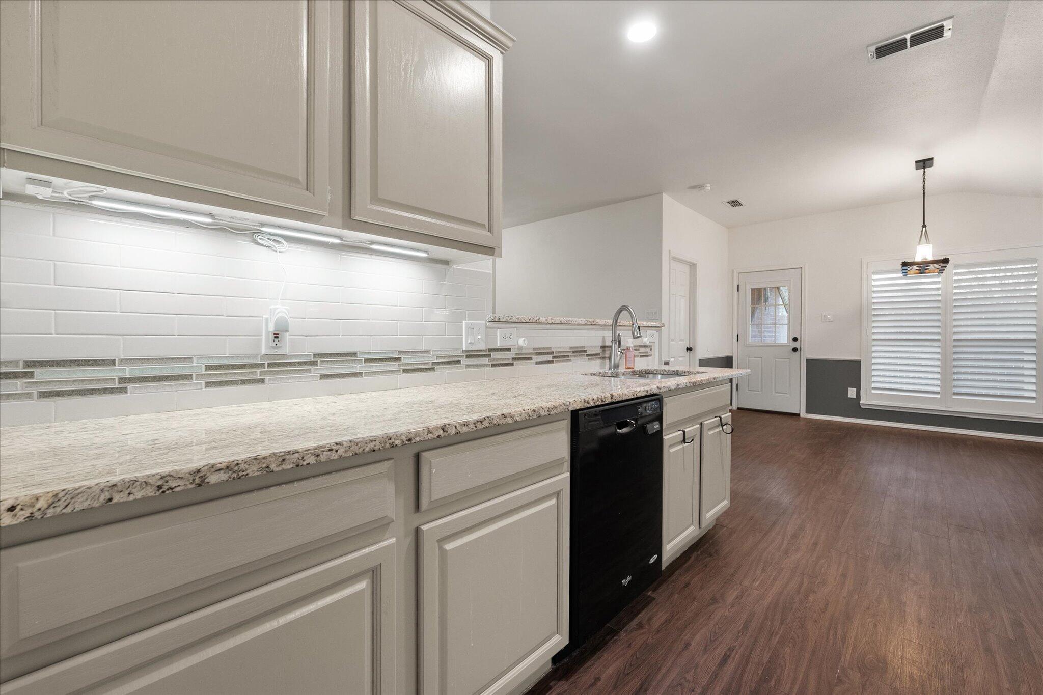 6104 Duke Street Lubbock, TX 79416 - Photo 15 of 28 a kitchen with kitchen island granite countertop a sink cabinets and wooden floor