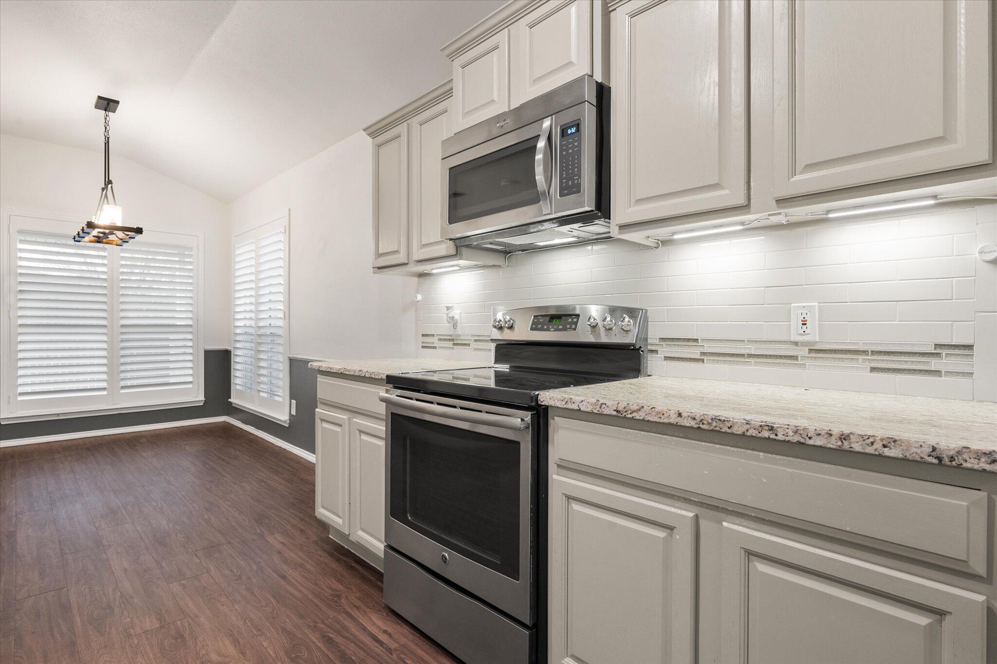 6104 Duke Street Lubbock, TX 79416 - Photo 16 of 28 a kitchen with granite countertop stainless steel appliances white cabinets granite counter tops and a wooden floor