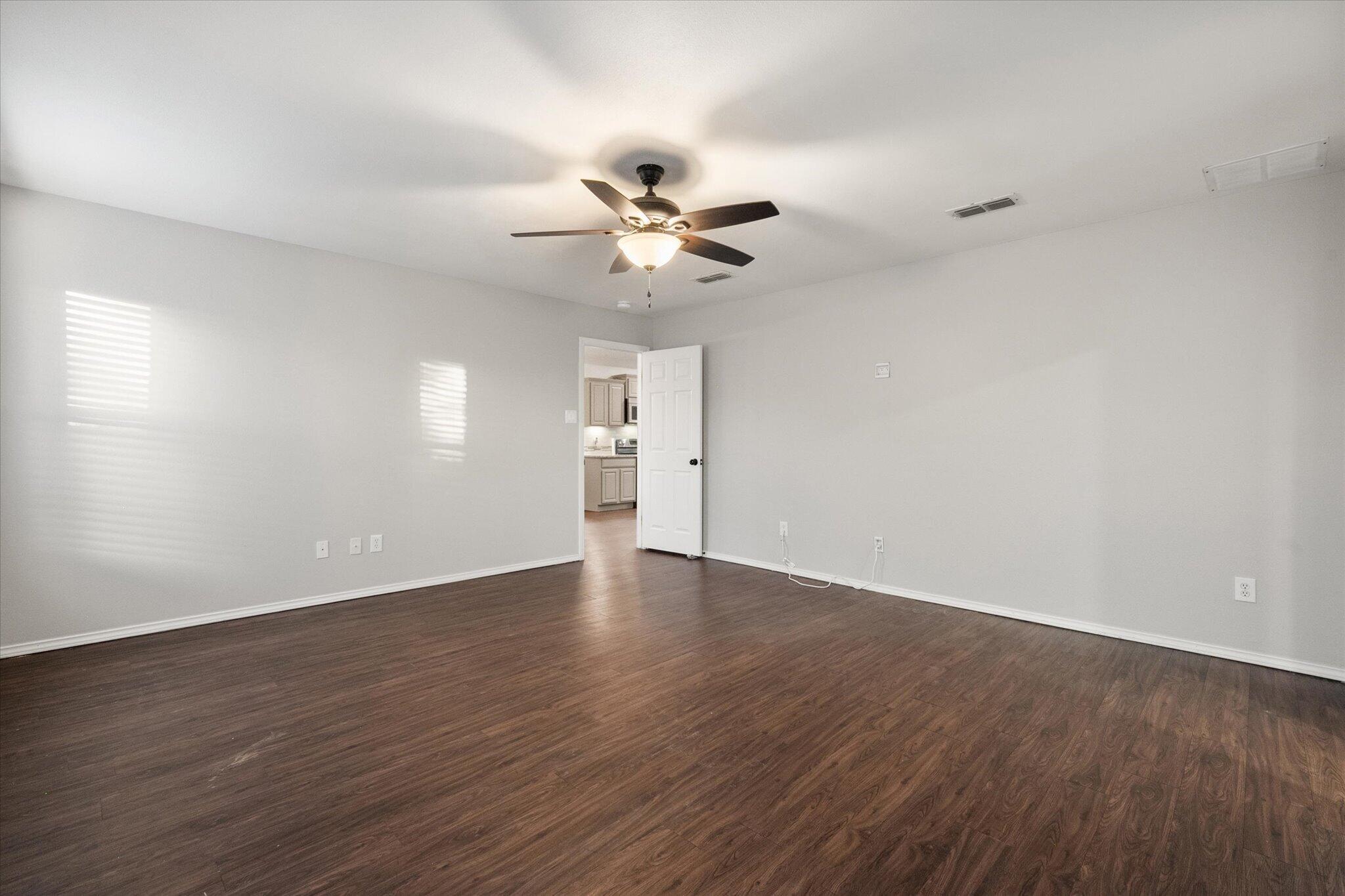 6104 Duke Street Lubbock, TX 79416 - Photo 22 of 28 a view of an empty room with a ceiling fan and wooden floor