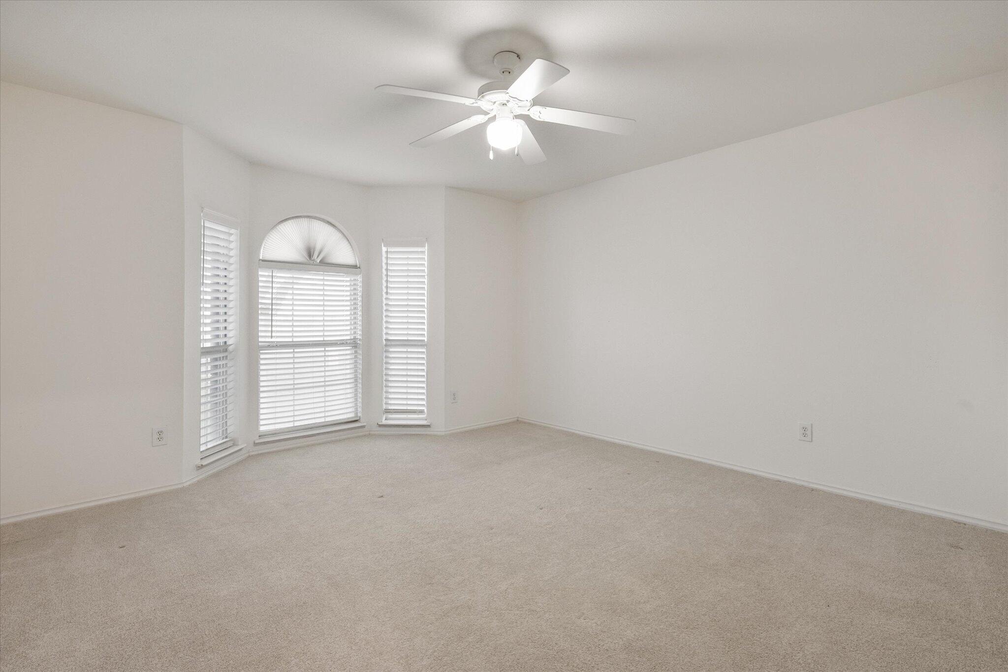 6104 Duke Street Lubbock, TX 79416 - Photo 5 of 28 an empty room with windows and ceiling fan