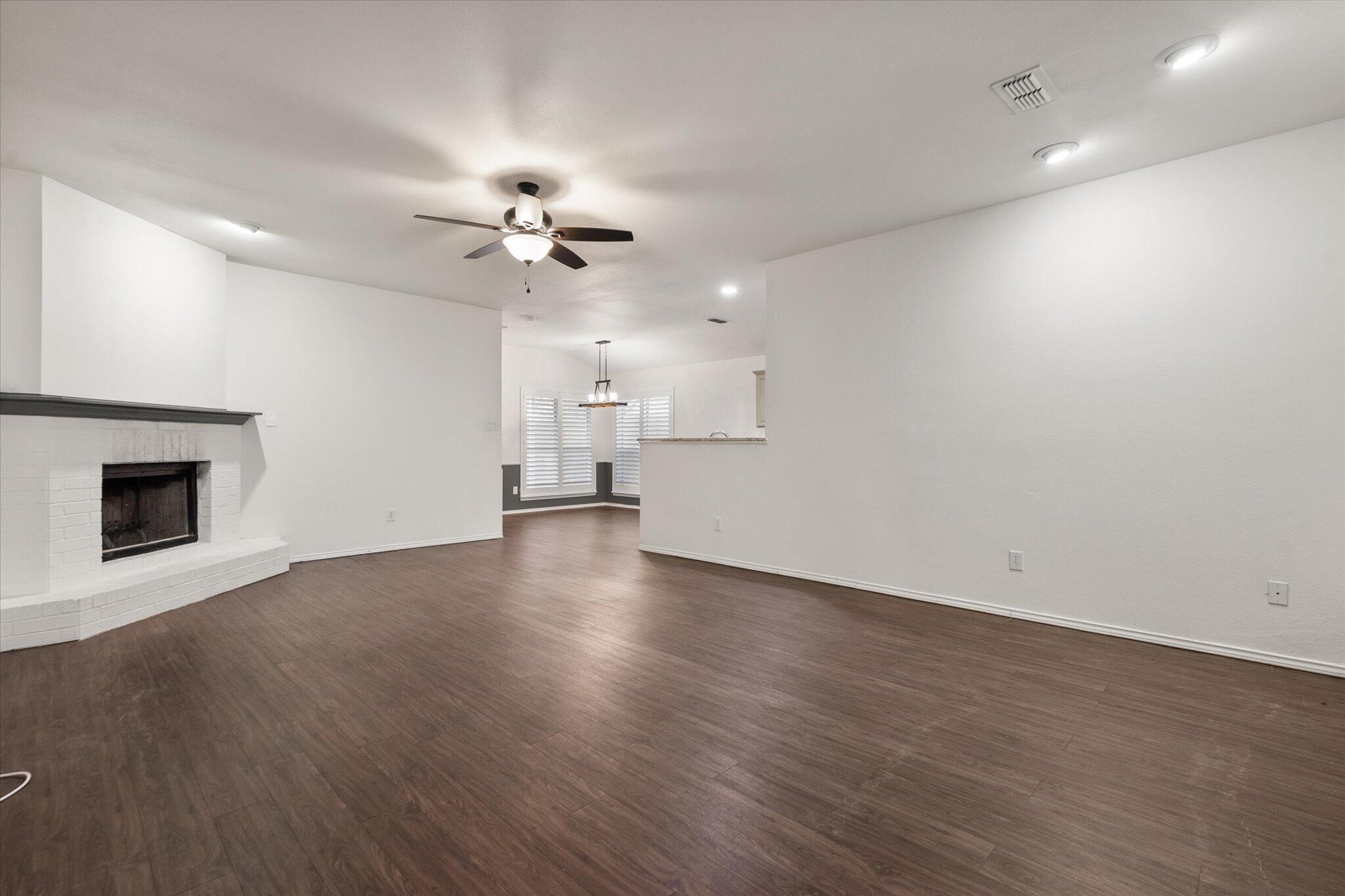 6104 Duke Street Lubbock, TX 79416 - Photo 8 of 28 an empty room with wooden floor ceiling fan and windows