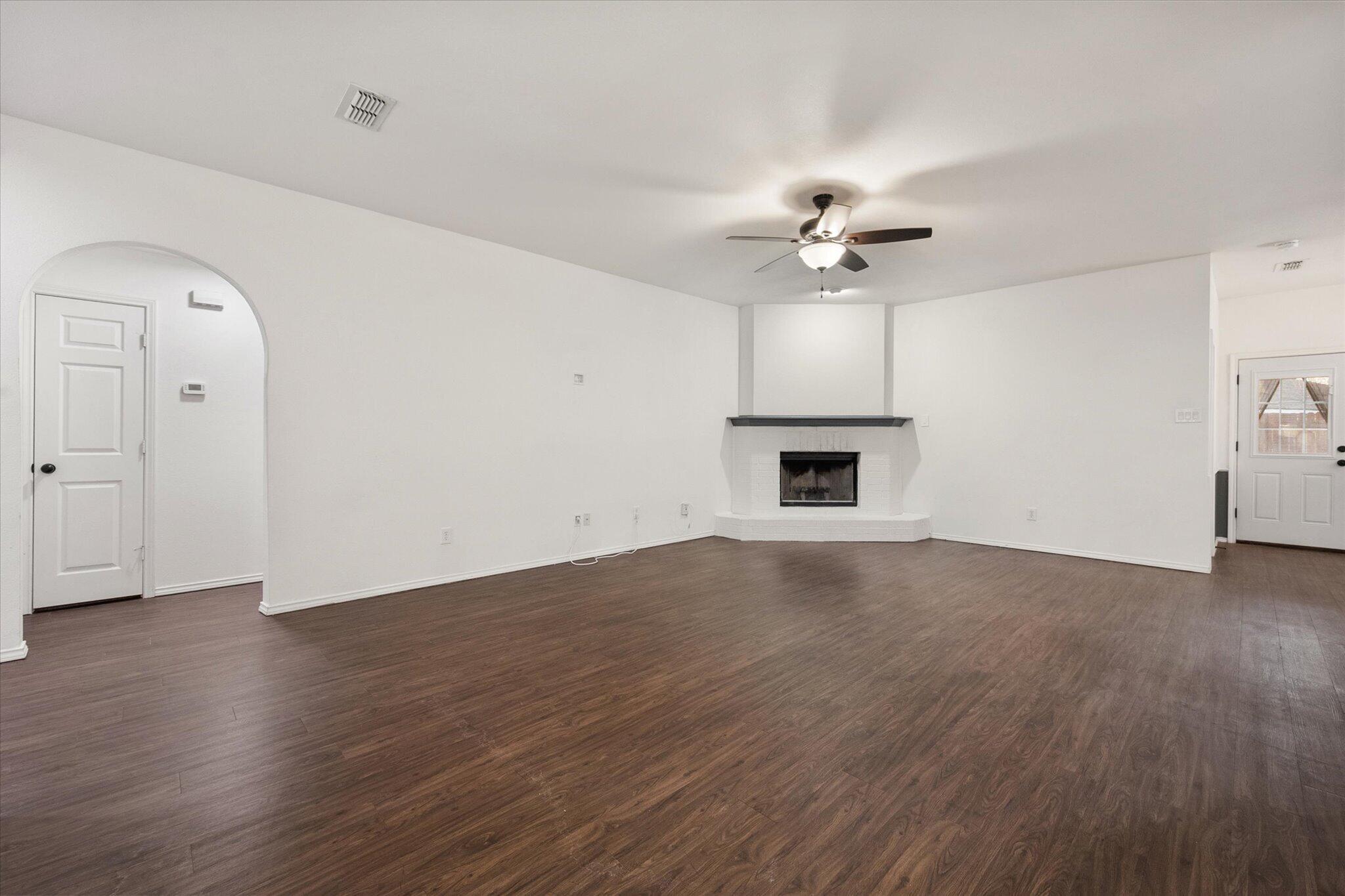 6104 Duke Street Lubbock, TX 79416 - Photo 9 of 28 an empty room with wooden floor ceiling fan and windows