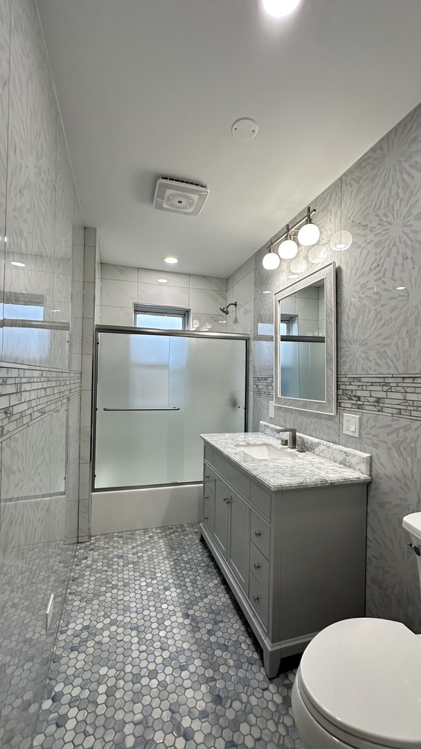 5226 North Bernard Street, Unit 2 Chicago, IL 60625 - Photo 7 of 12 a bathroom with a granite countertop sink a toilet and mirror
