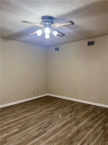 a view of an empty room with wooden floor and chandelier