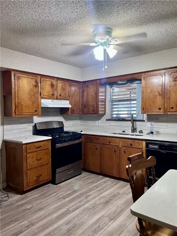 a kitchen with stainless steel appliances granite countertop a sink dishwasher stove and refrigerator