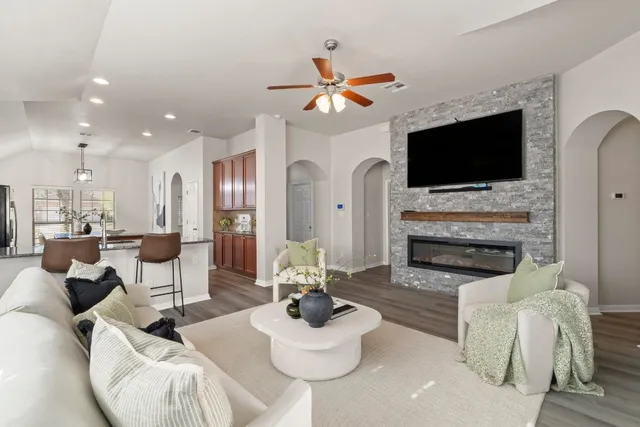 a living room with stainless steel appliances kitchen island granite countertop furniture a rug and a fireplace