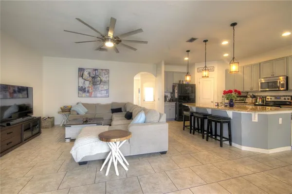 a living room with couches a dining table and kitchen view with wooden floor