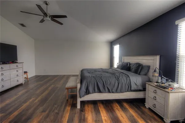 a spacious bedroom with a bed and a flat tv screen on dresser