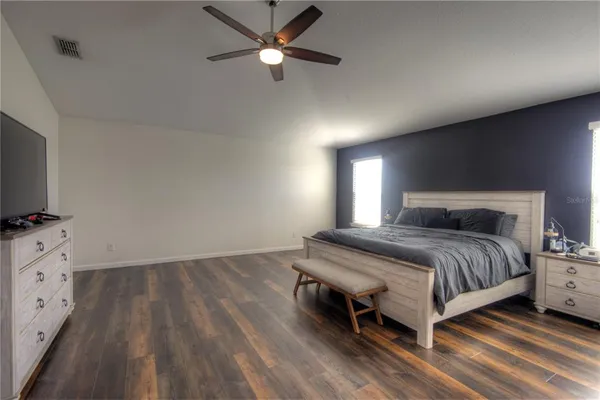 a bedroom with a bed and a flat tv screen on dresser