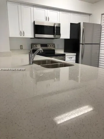 a kitchen with stainless steel appliances a refrigerator a sink a stove and microwave