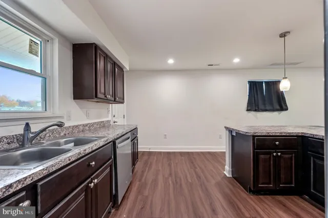 a kitchen with a sink dishwasher a refrigerator and a stove with wooden floor