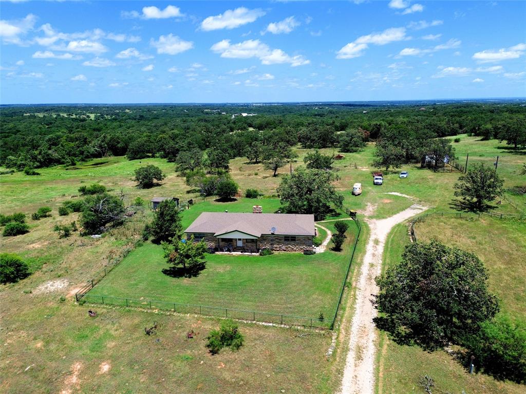 2186 Gilliland Road Springtown, TX 76082 - Photo 5 of 25 Expansive rural acreage featuring a single-story residence with a brown shingle roof and a stone facade