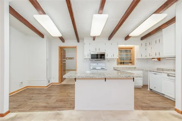 a kitchen with stainless steel appliances granite countertop a stove a sink dishwasher and a refrigerator with white cabinets