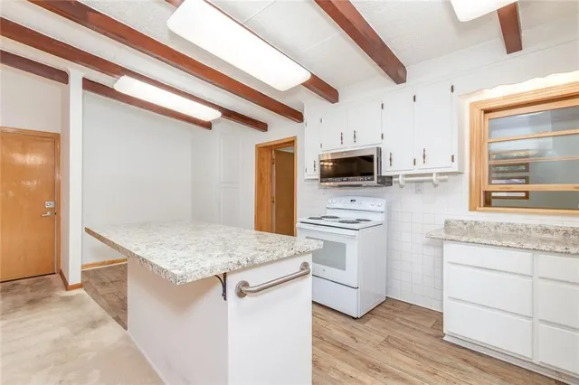 a kitchen with stainless steel appliances kitchen island a stove a microwave and a refrigerator