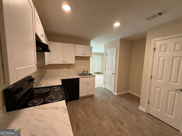 a kitchen with granite countertop a sink a stove a refrigerator and cabinets