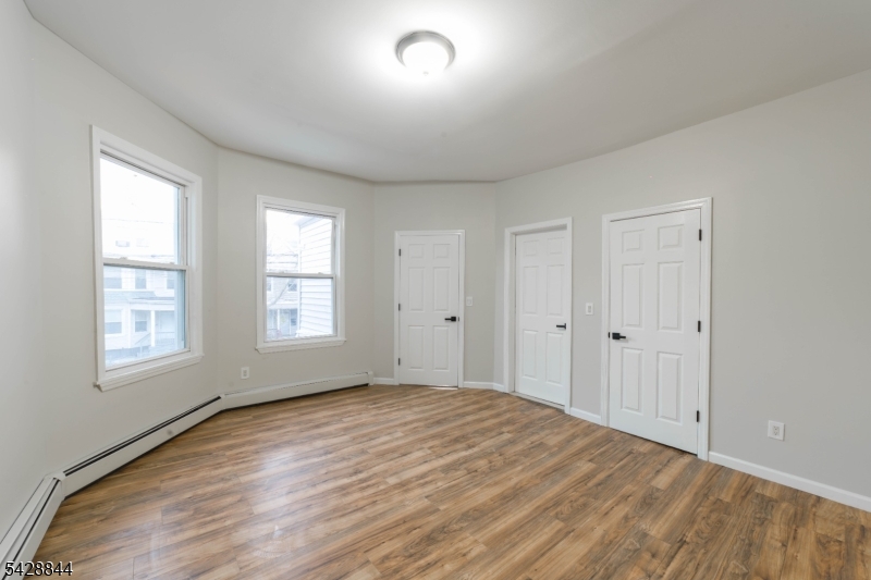 874 South 16th Street Newark, NJ 07108 - Photo 11 of 22 an empty room with wooden floor and windows
