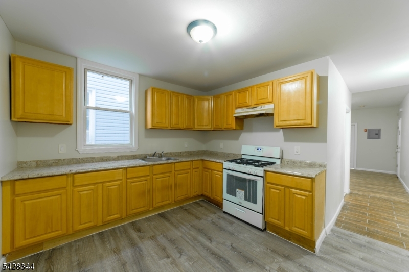 874 South 16th Street Newark, NJ 07108 - Photo 18 of 22 a kitchen with stainless steel appliances granite countertop wooden cabinets a stove a sink and a window