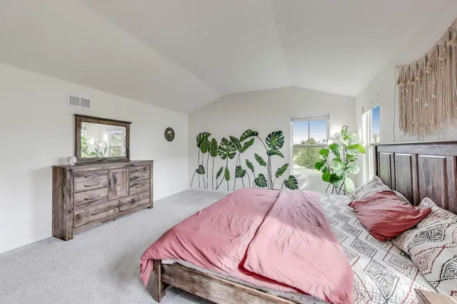 a bedroom with a bed and dresser with potted plants