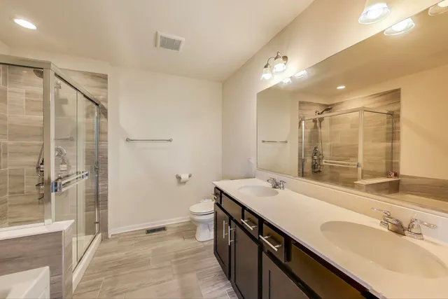 a bathroom with a double vanity sink mirror and shower