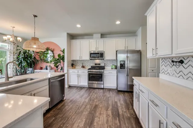 a kitchen with granite countertop a refrigerator a stove top oven a sink and dishwasher with wooden floor