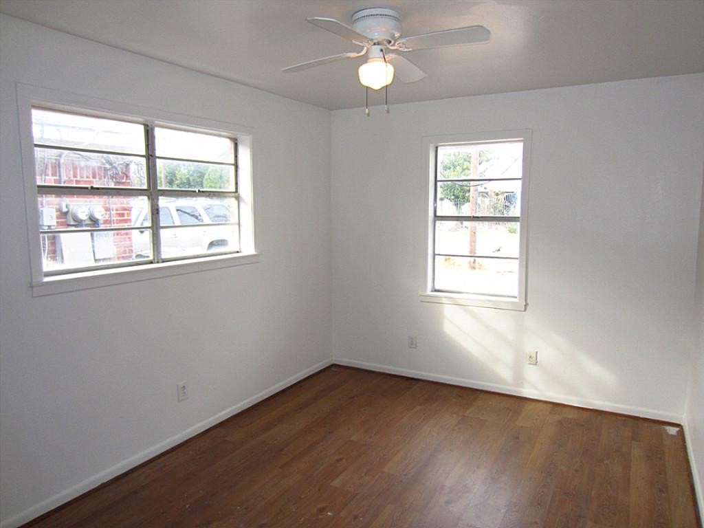 3810 Cochran Street Houston, TX 77009 - Photo 11 of 12 an empty room with wooden floor windows and a ceiling fan