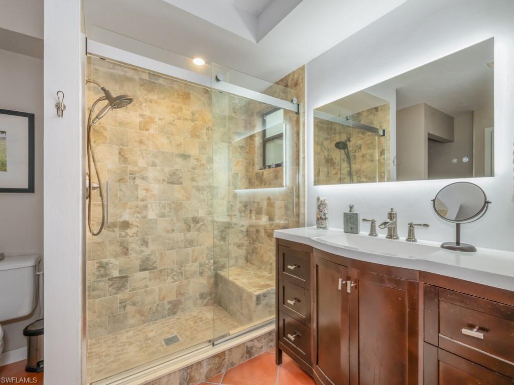 1271 Solana Road, Unit E4 Naples, FL 34103 - Photo 13 of 21 a bathroom with a granite countertop sink a mirror and a shower