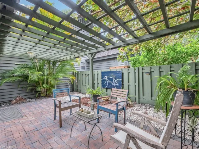 a view of patio with a table and chairs and couches with wooden fence and plants