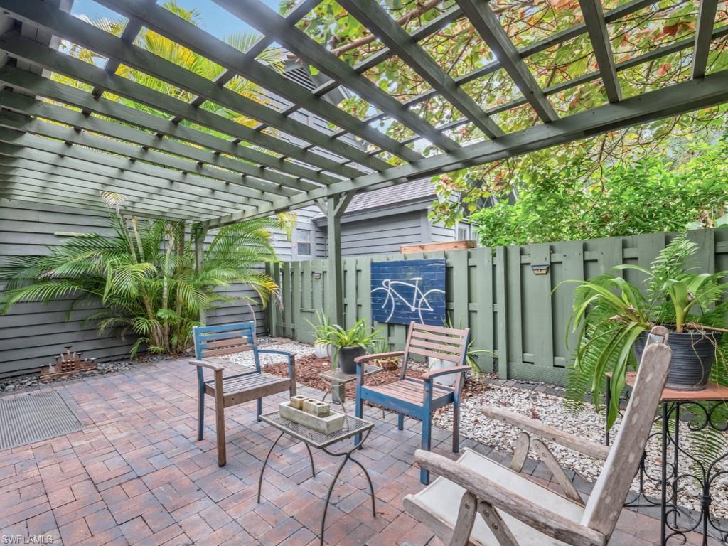 1271 Solana Road, Unit E4 Naples, FL 34103 - Photo 4 of 21 a view of patio with a table and chairs and couches with wooden fence and plants