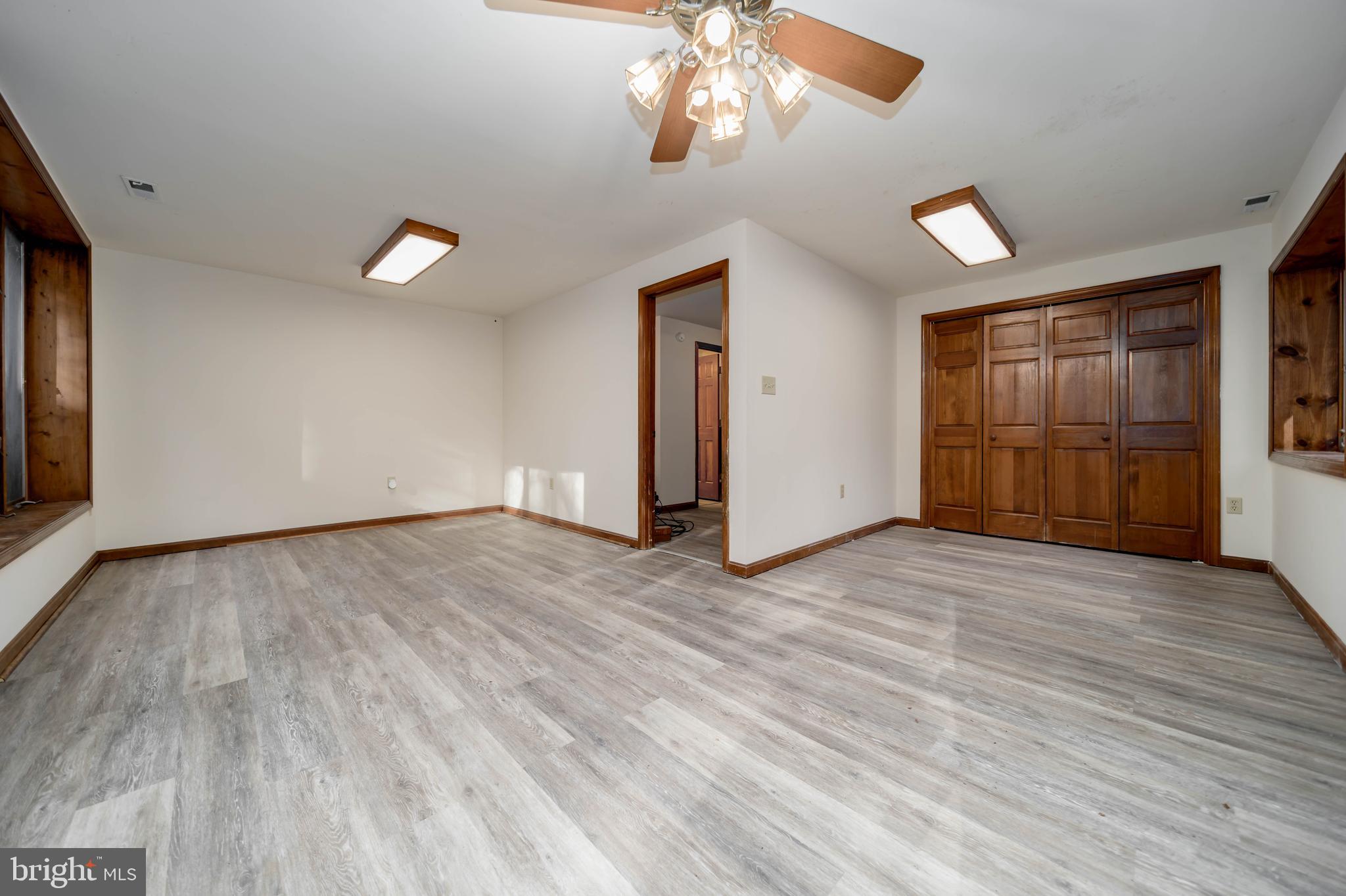 5510 Stephen Reid Road Huntingtown, MD 20639 - Photo 9 of 59 an empty room with wooden floor cabinet and windows