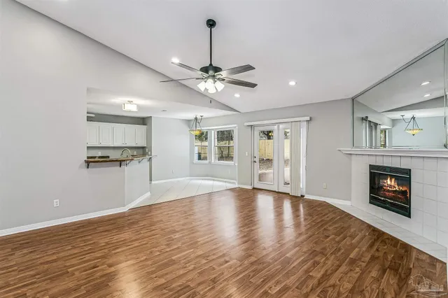 a view of an empty room with wooden floor fireplace and a window