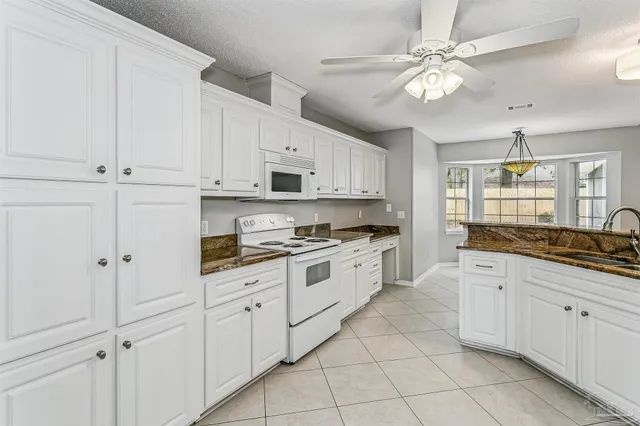 a large white kitchen with stainless steel appliances granite countertop lots of white cabinets